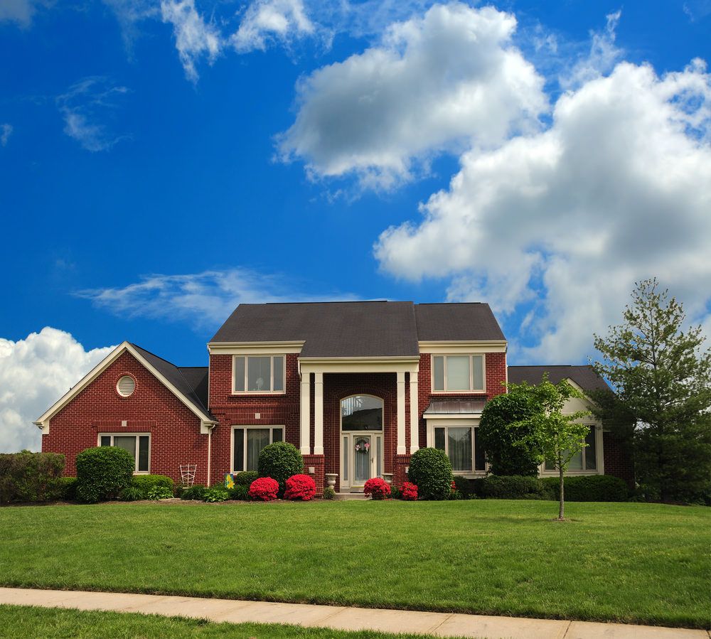 2 story symmetrical home with bright red brick and columns flanking the